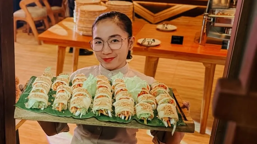 Daloy Bistro staff presenting a tray of freshly prepared rolls inside the restaurant.
