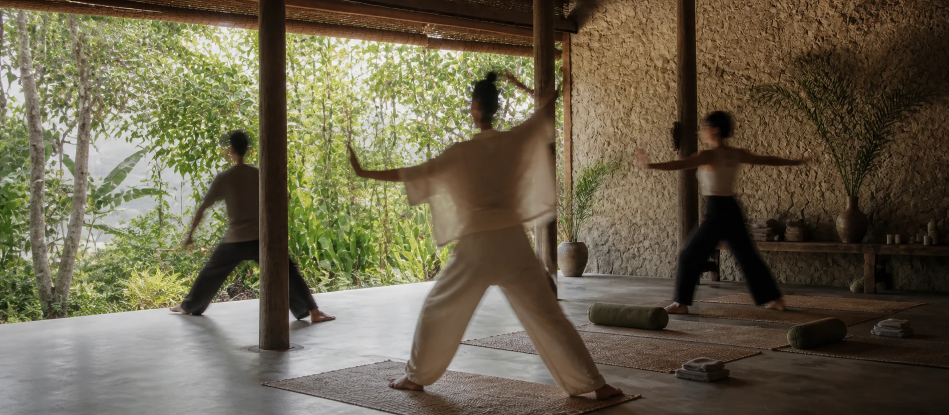 People move gently through an open-air forest pavilion, their faces obscured by motion blur.